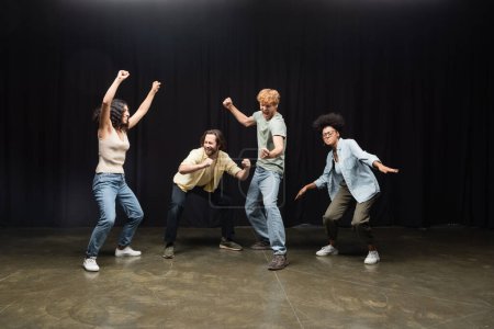 full length of excited interracial students posing in acting skills studio