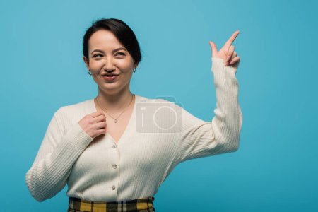 Photo for Sly asian woman pointing with finger isolated on blue - Royalty Free Image