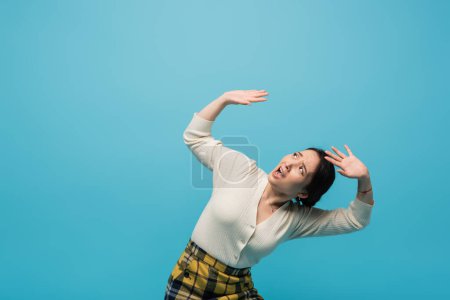 Scared asian woman looking up isolated on blue 
