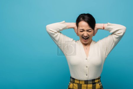 Angry asian woman screaming isolated on blue 