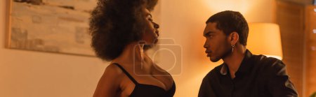 Téléchargez les photos : Femme américaine africaine sexy en soutien-gorge près de jeune petit ami en chemise noire dans la chambre à coucher à la maison, bannière - en image libre de droit