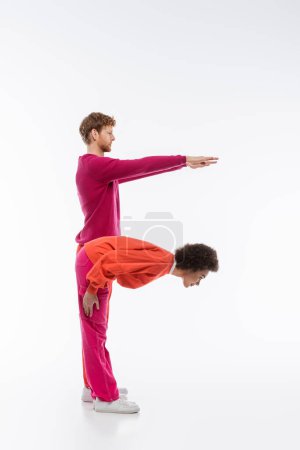 Photo for Side view of multiethnic man and woman in magenta color clothes showing f letter on white background - Royalty Free Image