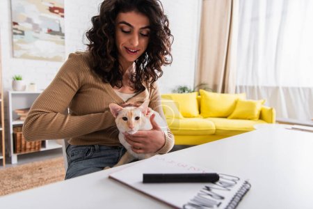 Téléchargez les photos : Brunette copywriter petting oriental cat in living room - en image libre de droit