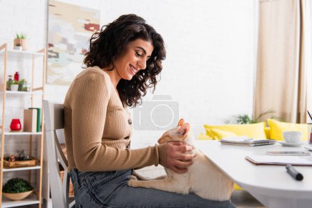 Copywriter petting oriental cat near laptop and coffee at home 