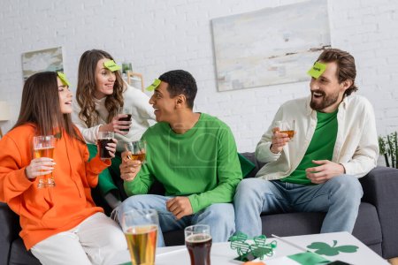 alegre interracial amigos con bebidas jugando quien soy juego mientras celebrando santo patrick día 
