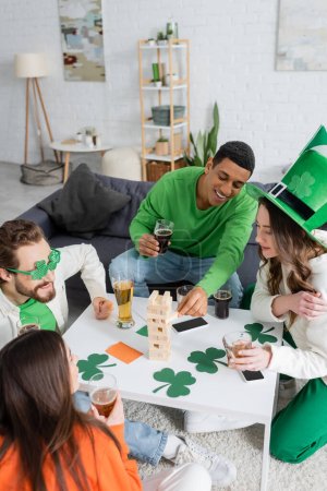 African american man playing wood blocks game with friends during saint patrick day celebration 