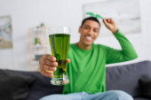 Blurred african american man holding green beer at home  Sweatshirt #639066838