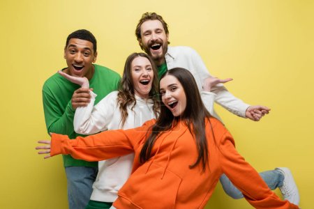 Excited interracial friends having fun on yellow background 