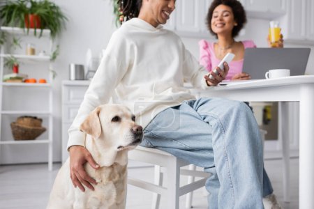 Labrador sitting near african american couple with devices in kitchen 