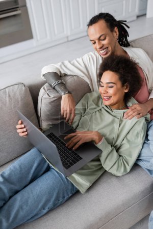 Téléchargez les photos : High angle view of excited african american couple using laptop on couch - en image libre de droit