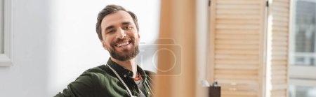 Photo for Positive carpenter looking at camera in workshop, banner - Royalty Free Image