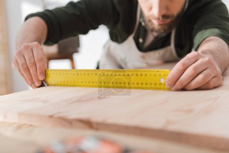 Téléchargez les photos : Cropped view of blurred craftsman holding square tool near wooden board - en image libre de droit