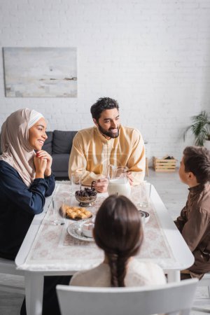 Photo for Smiling muslim family talking near food during ramadan at home - Royalty Free Image