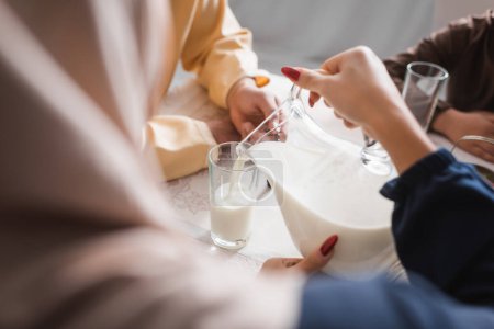 Photo for Arabian woman pouring milk during suhur with family in morning at home - Royalty Free Image