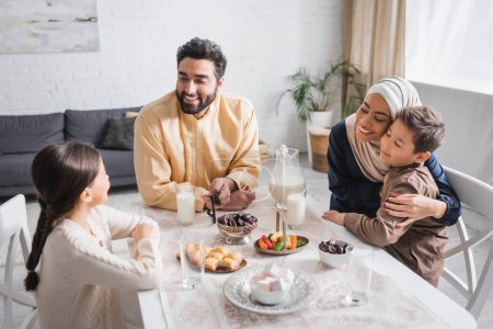 Photo for Positive muslim family sitting near food during suhur in morning at home - Royalty Free Image