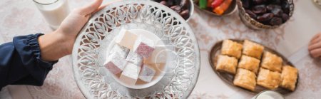 Photo for Top view of muslim woman holding plate with turkish delight during suhur and ramadan, banner - Royalty Free Image
