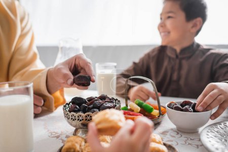 Téléchargez les photos : Musulman prenant date fruits près des enfants pendant le petit déjeuner suhur à la maison - en image libre de droit