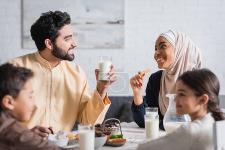 Photo for Happy muslim parents looking at each other near blurred kids and suhur breakfast at home - Royalty Free Image