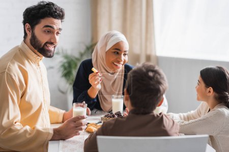 Photo for Muslim father talking to son near happy family during suhur breakfast - Royalty Free Image