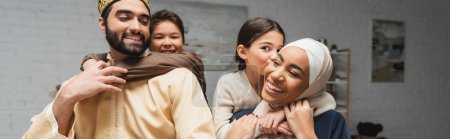Téléchargez les photos : Positive middle eastern family with kids hugging at home, banner - en image libre de droit