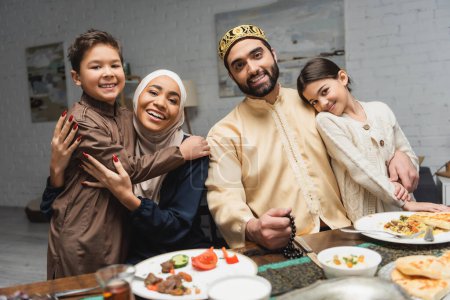 Photo for Middle eastern family hugging kids during ramadan dinner at home - Royalty Free Image