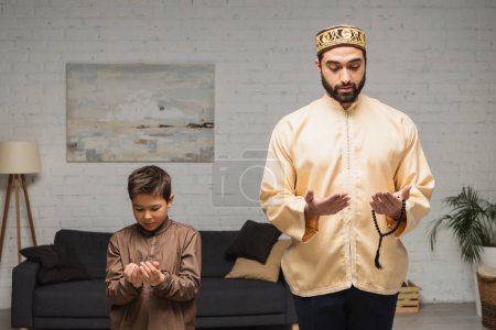 Bliskowschodni mężczyzna i dziecko modlący się podczas salah w domu 