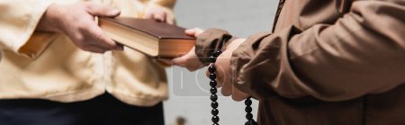 Photo for Cropped view of muslim father giving book to son with prayer beads at home, banner - Royalty Free Image