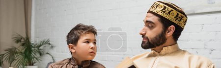 Photo for Middle eastern man looking at son near blurred book at home, banner - Royalty Free Image