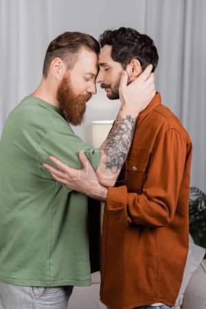 Photo for Side view of bearded same sex couple hugging in living room - Royalty Free Image