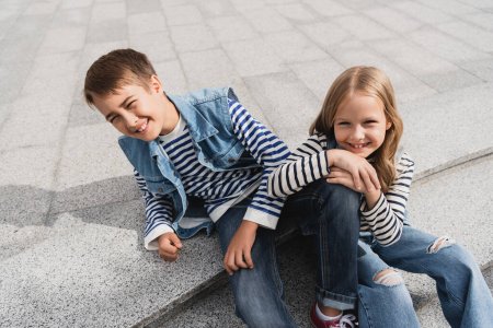 vue grand angle des enfants heureux et bien habillés assis sur les escaliers dans la rue urbaine 