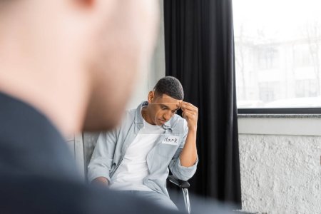 Homme afro-américain frustré avec dépendance à l'alcool assis dans un centre de désintox 