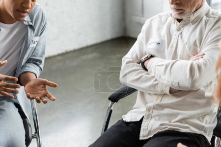 Photo for Cropped view of african american person talking to man during alcoholics meeting in rehab center - Royalty Free Image