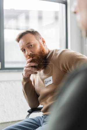 Bearded man with alcohol addiction looking at member of aa group in rehab center 