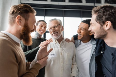Positive multiethnische Gruppe umarmt Mann mittleren Alters bei Alkoholikertreffen in der Reha 