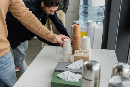 Man with alcohol addiction taking paper cup in rehab center 
