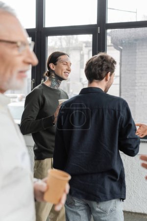 Téléchargez les photos : Hommes positifs avec des gobelets en papier parlant pendant la réunion des alcooliques dans le centre de récupération - en image libre de droit
