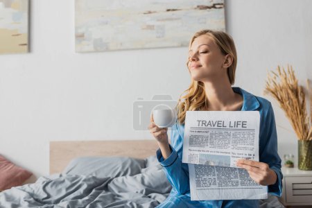 Téléchargez les photos : Heureux jeune femme tenant la vie de voyage journal et tasse de café dans la chambre - en image libre de droit