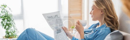 Téléchargez les photos : Vue latérale de la jeune femme insouciante lisant le journal de voyage et tenant une tasse de café dans la chambre, bannière - en image libre de droit