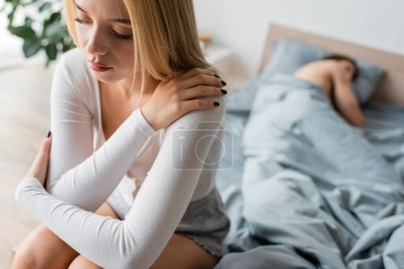 Foto de Mujer avergonzada sentada en la cama después de una noche con el hombre en su dormitorio - Imagen libre de derechos
