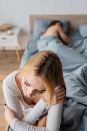 Untreue junge Frau sitzt nach One-Night-Stand mit Mann im Schlafzimmer im Bett 