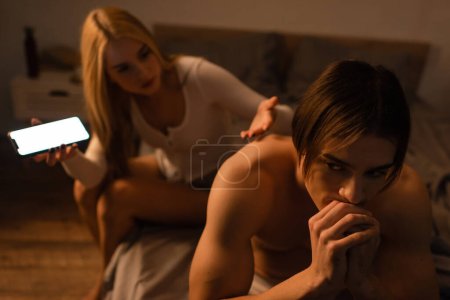 mujer molesta sosteniendo teléfono inteligente mientras discute con el hombre infiel en la noche, concepto de engaño 