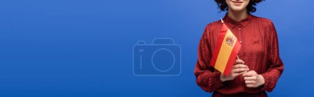 Photo for Cropped view of happy language teacher smiling while holding flag of Spain isolated on blue, banner - Royalty Free Image