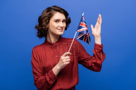 happy language teacher holding flag of United Kingdom isolated on blue  Poster 645931568