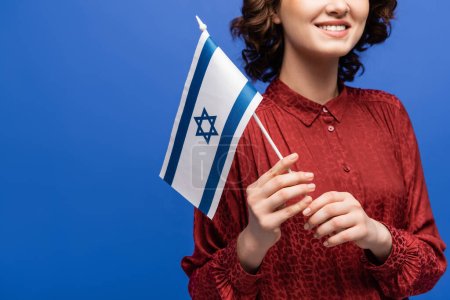 vue recadrée d'un enseignant hébreu souriant tenant le drapeau d'Israël isolé sur bleu