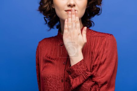 Foto de Vista recortada de la mujer en blusa roja diciendo gracias en el lenguaje de señas aislado en azul - Imagen libre de derechos