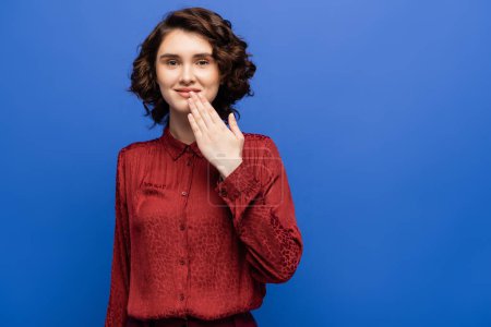 Téléchargez les photos : Heureux jeune femme dire merci sur langue des signes isolé sur bleu - en image libre de droit