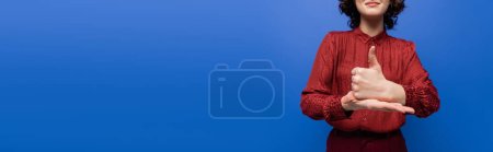 Photo for Cropped view of joyful woman showing help gesture on sign language isolated on blue, banner - Royalty Free Image