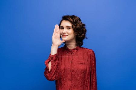 Photo for Cheerful teacher showing gesture meaning woman or mother on sign language isolated on blue - Royalty Free Image