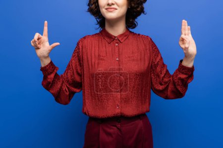 cropped view of pleased teacher showing alphabet letters on sign language isolated on blue