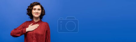Photo for Happy brunette woman telling please on sign language isolated on blue, banner - Royalty Free Image